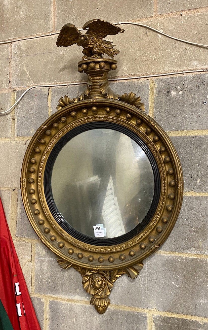 A large Regency carved giltwood convex wall mirror with eagle pediment, replaced plate, width 65cm, height 108cm